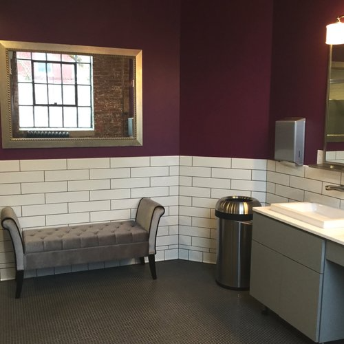 A bathroom with a bench and a trash can