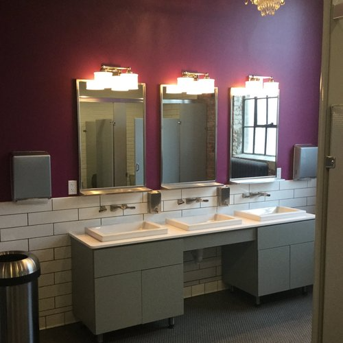 A bathroom with three sinks and three mirrors