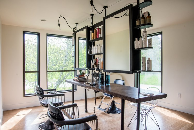 A hair salon with chairs , a table and a mirror.