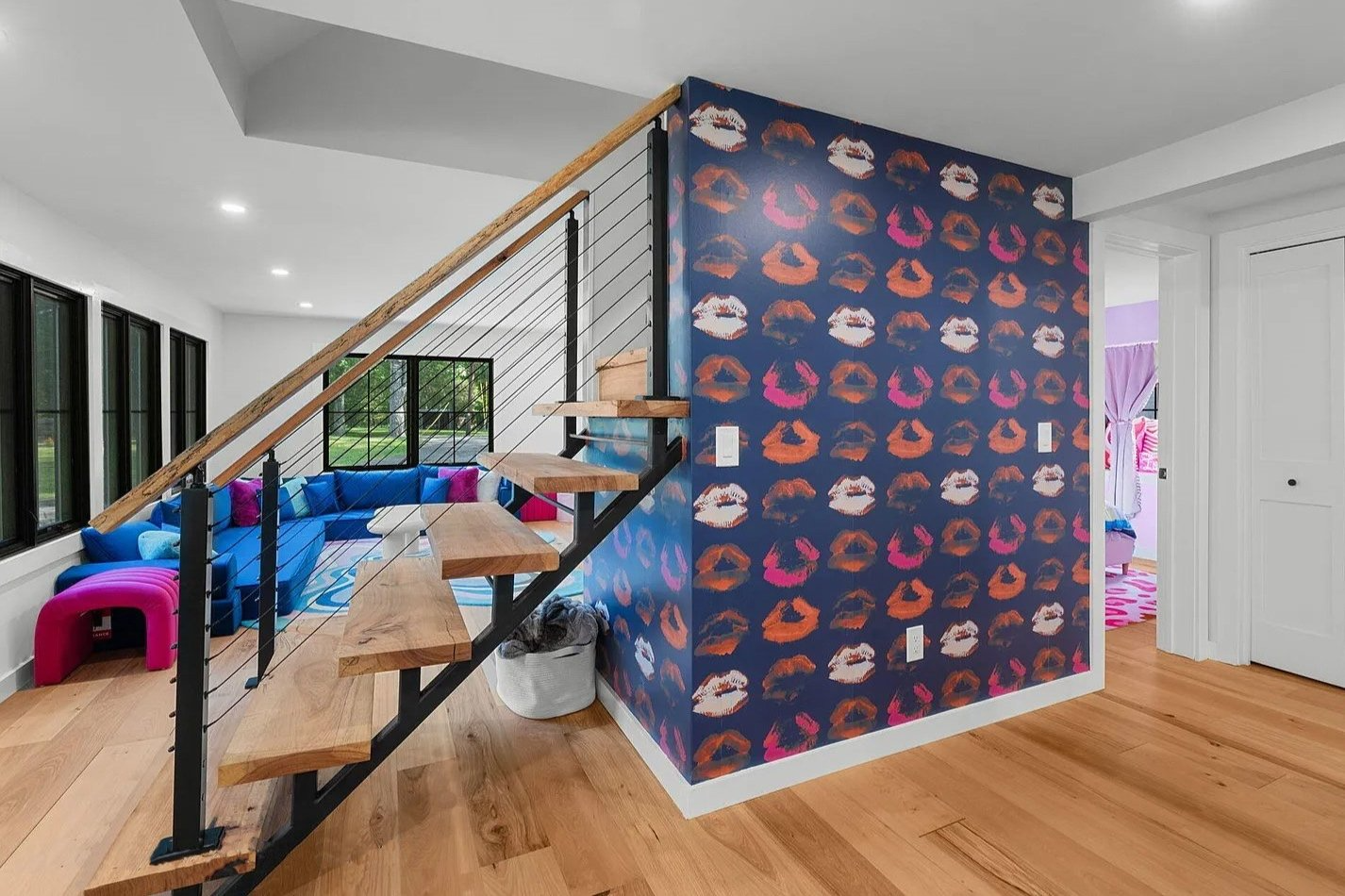 A living room with a staircase and a wall with a pattern of kisses on it.