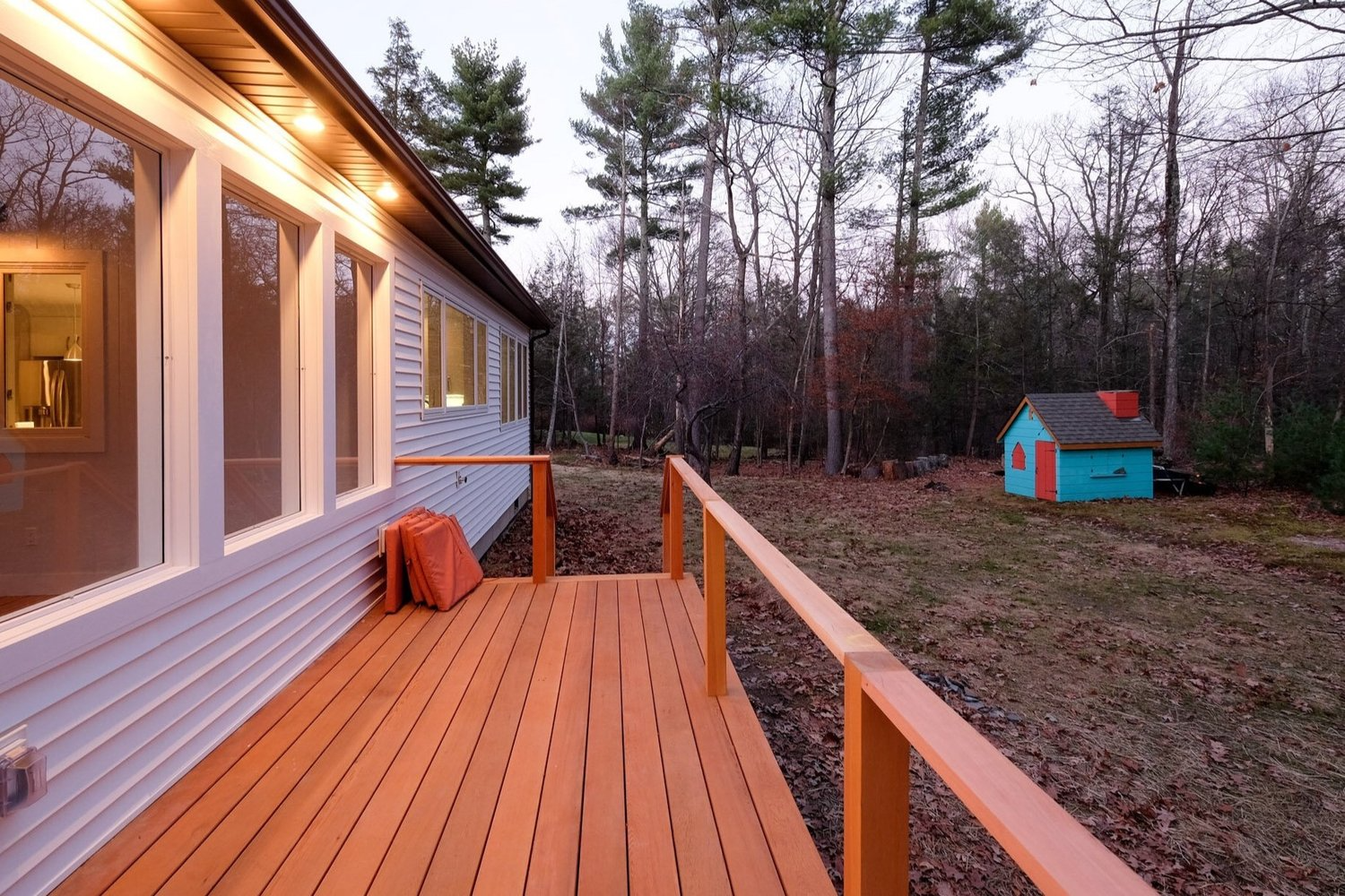 A house with a wooden deck and a blue shed in the backyard