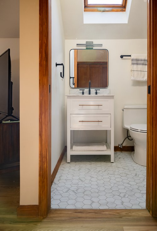 A bathroom with a sink , toilet , mirror and skylight.