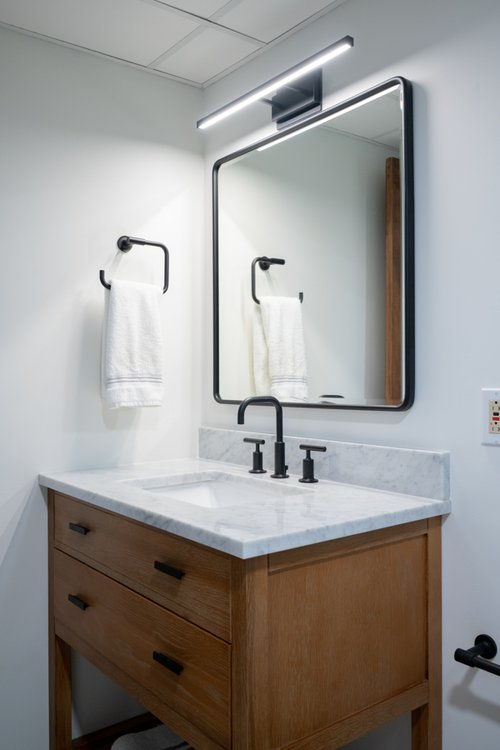 A bathroom with a sink , mirror and towel rack.