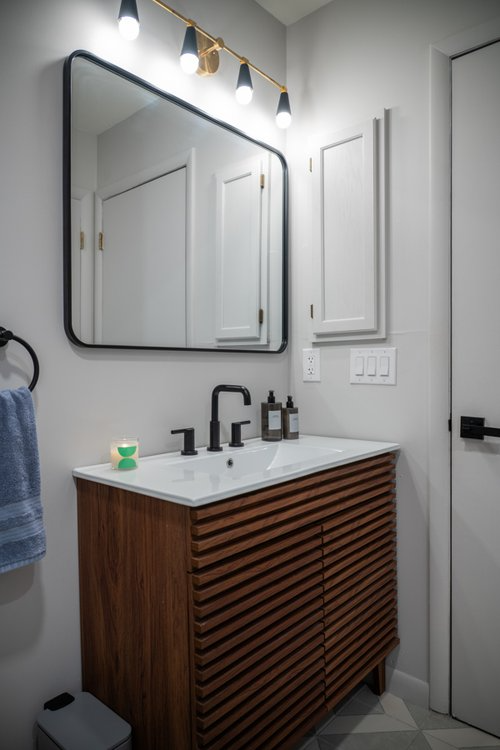 A bathroom with a sink , mirror and towel rack.
