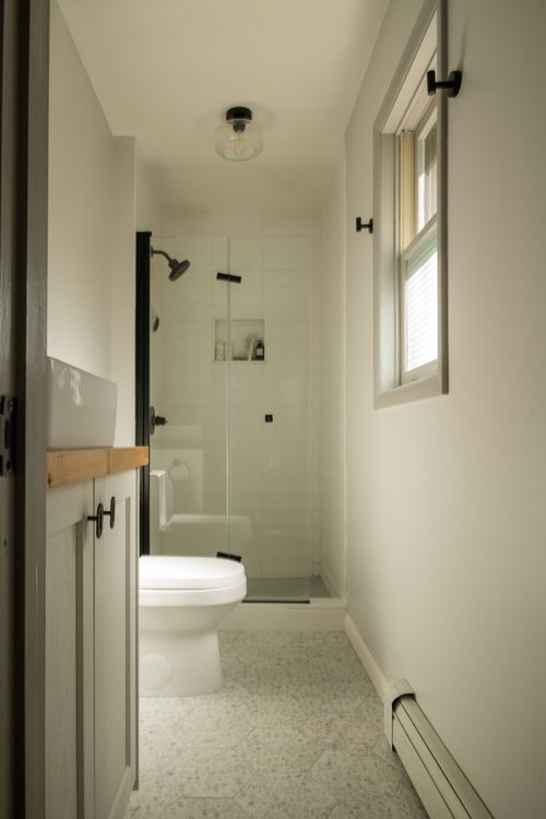 A bathroom with a toilet a shower and a window