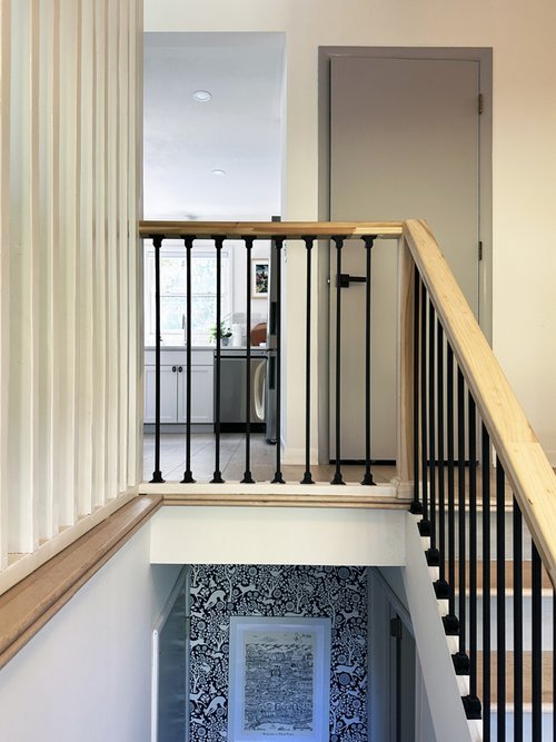 A staircase with a wooden railing and a black railing