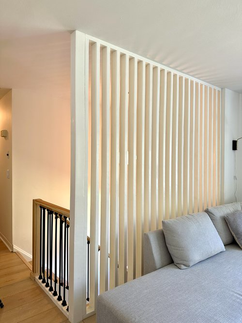 A living room with a couch and a wooden divider between the stairs and the living room.