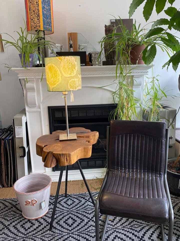 A living room with a lamp , chair , table and fireplace.