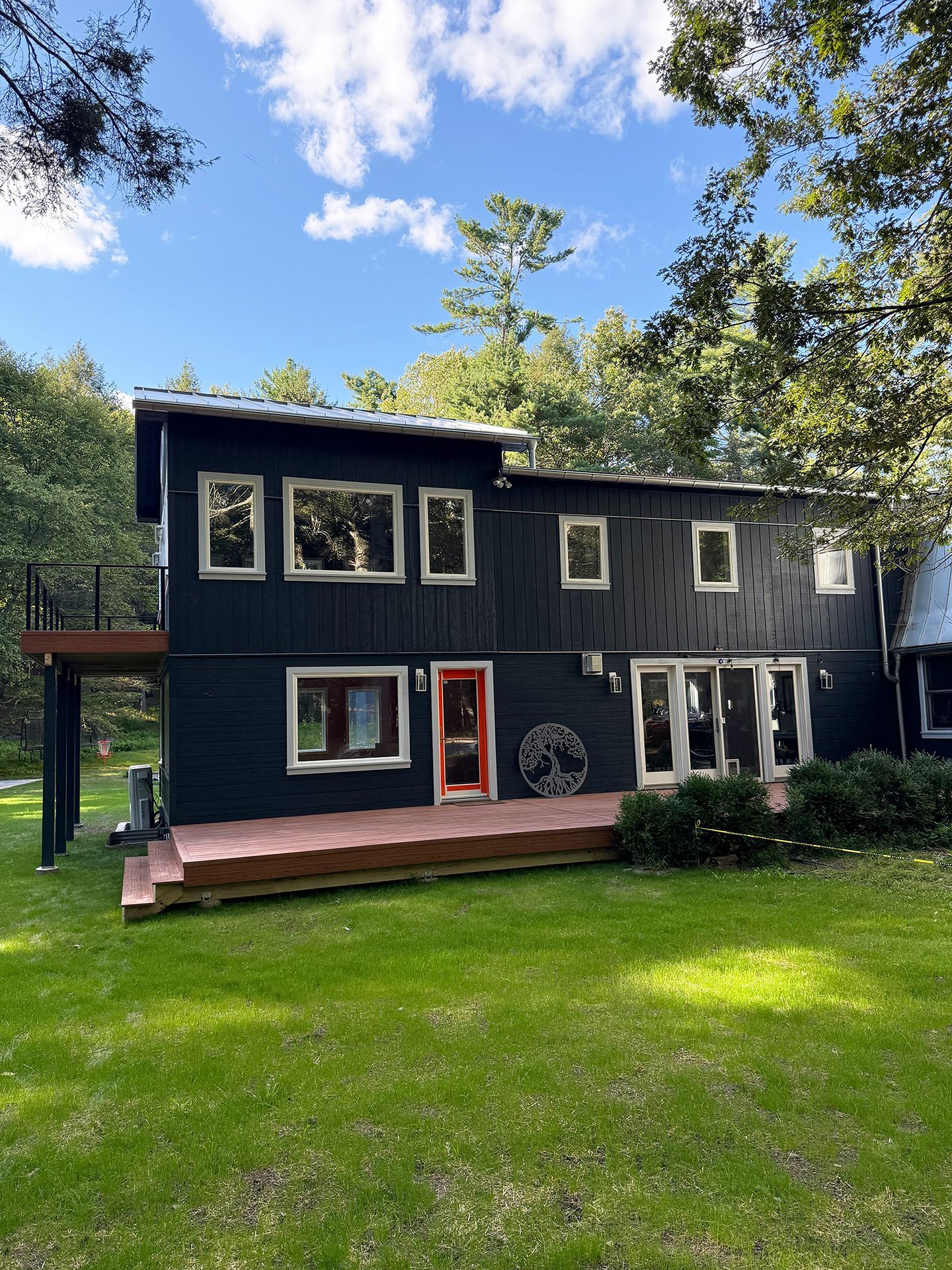 A two-story dark exterior house with a wooden deck and large windows