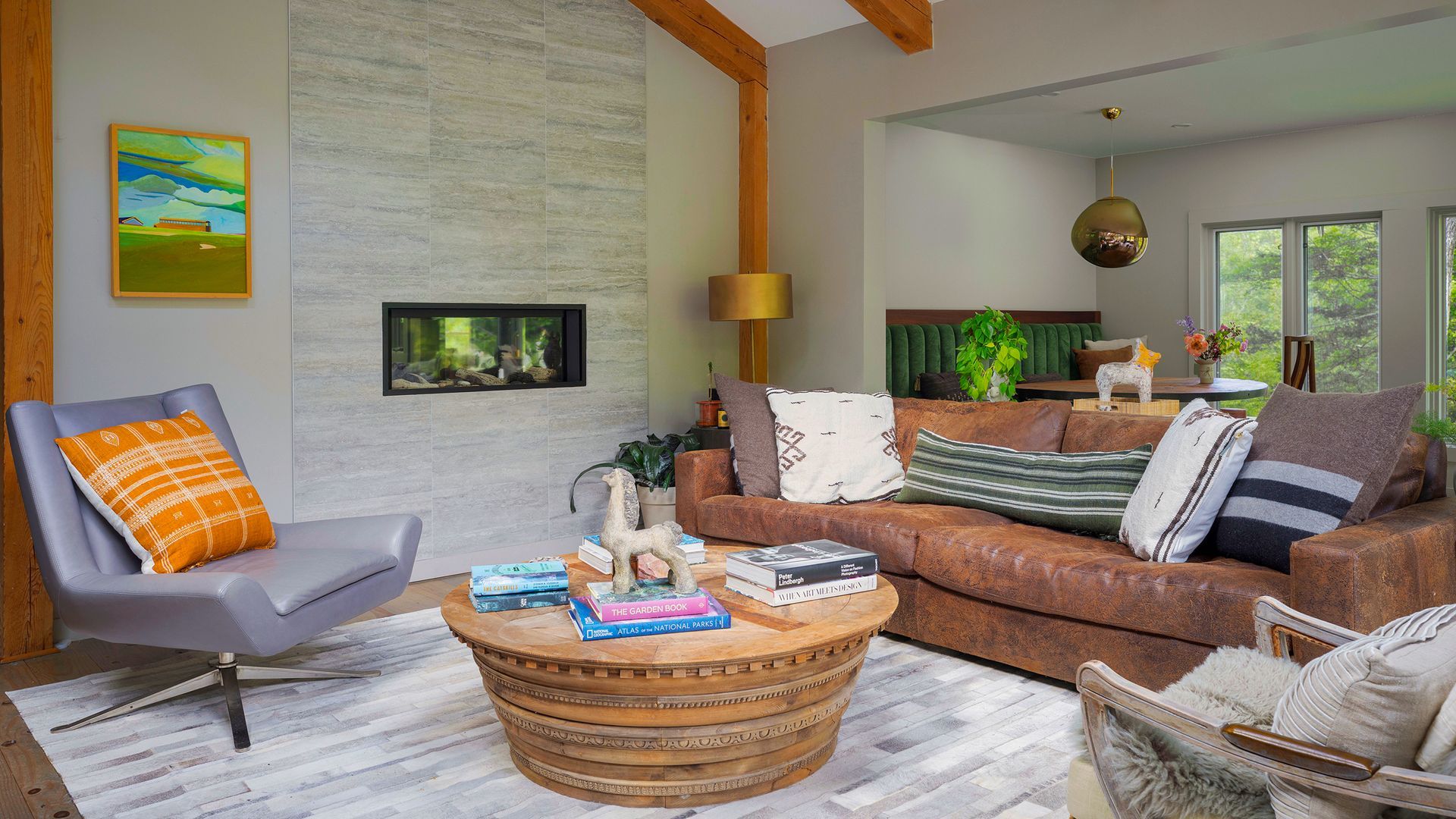 A living room with a brown leather sofa, grey armchair, textured wood coffee table