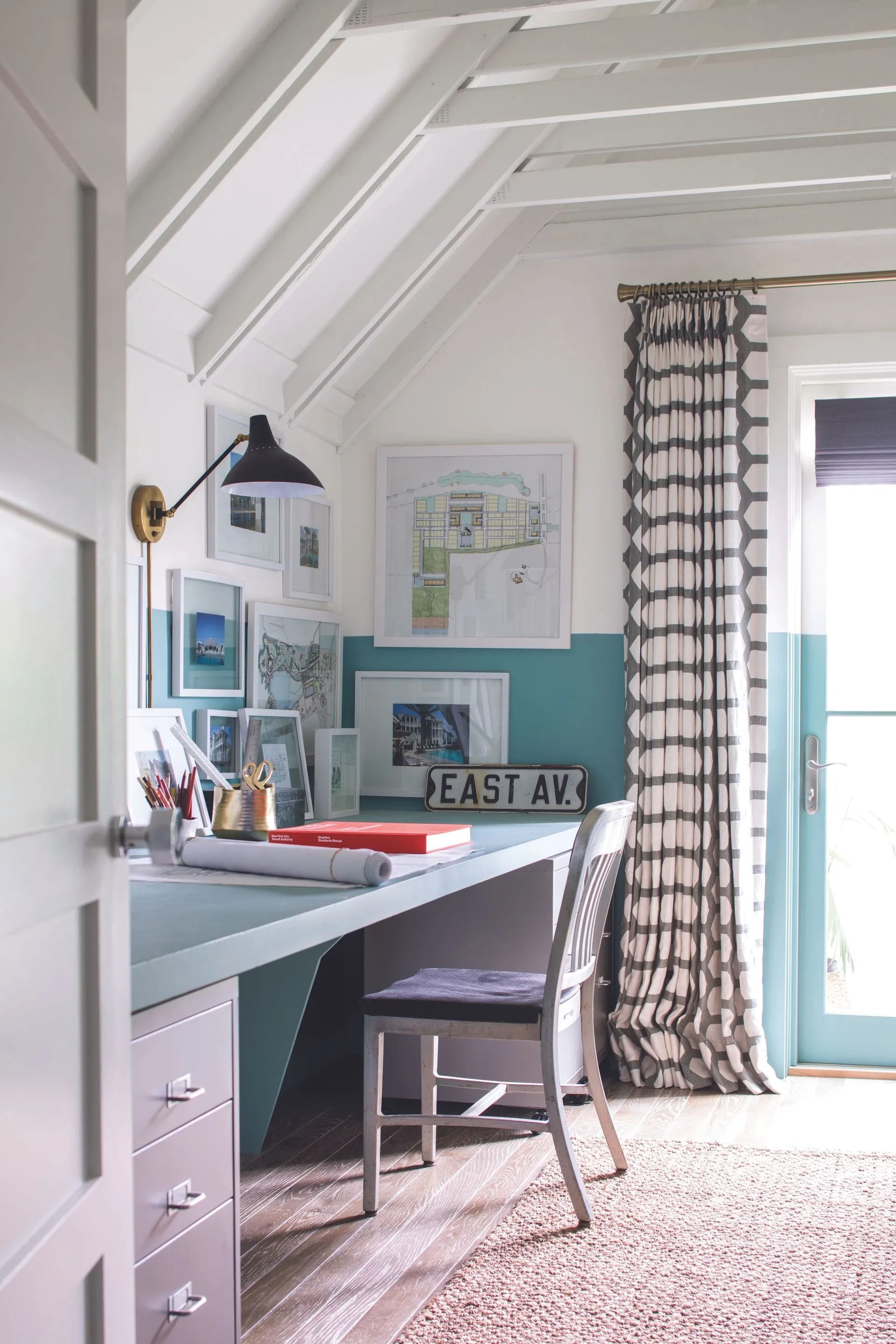 Bright home office with desk, chair, wall art, striped curtains, and a skylight ceiling