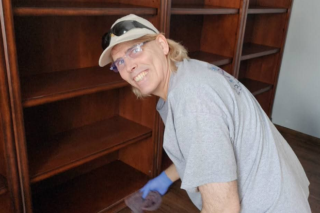 Man cleaning bookshelf