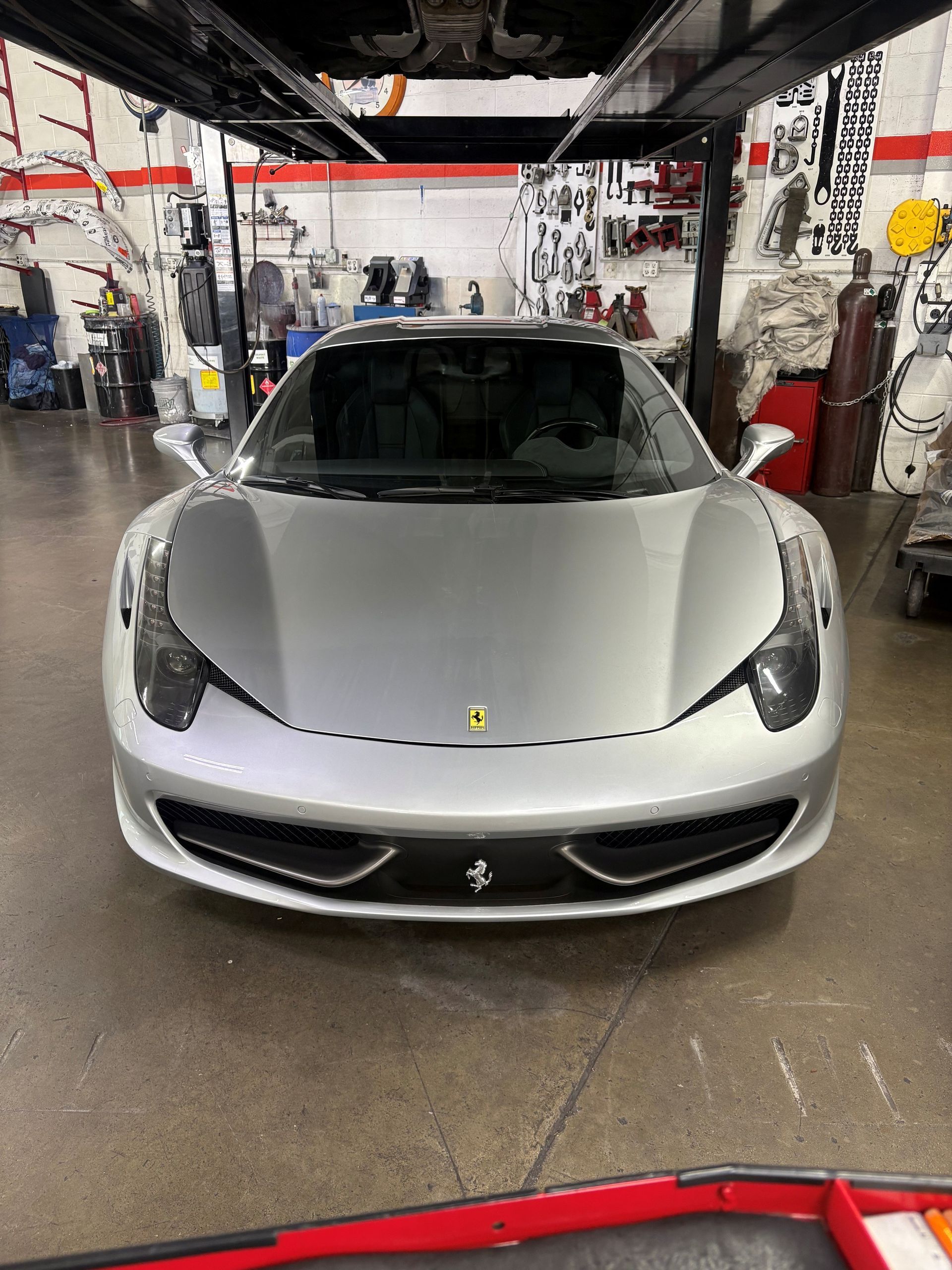 Silver sports car in an auto shop, front view, with tools and equipment in the background
