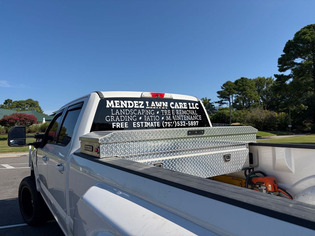 White pickup truck with a large chrome toolbox and business decals parked outdoors under a clear blue sky