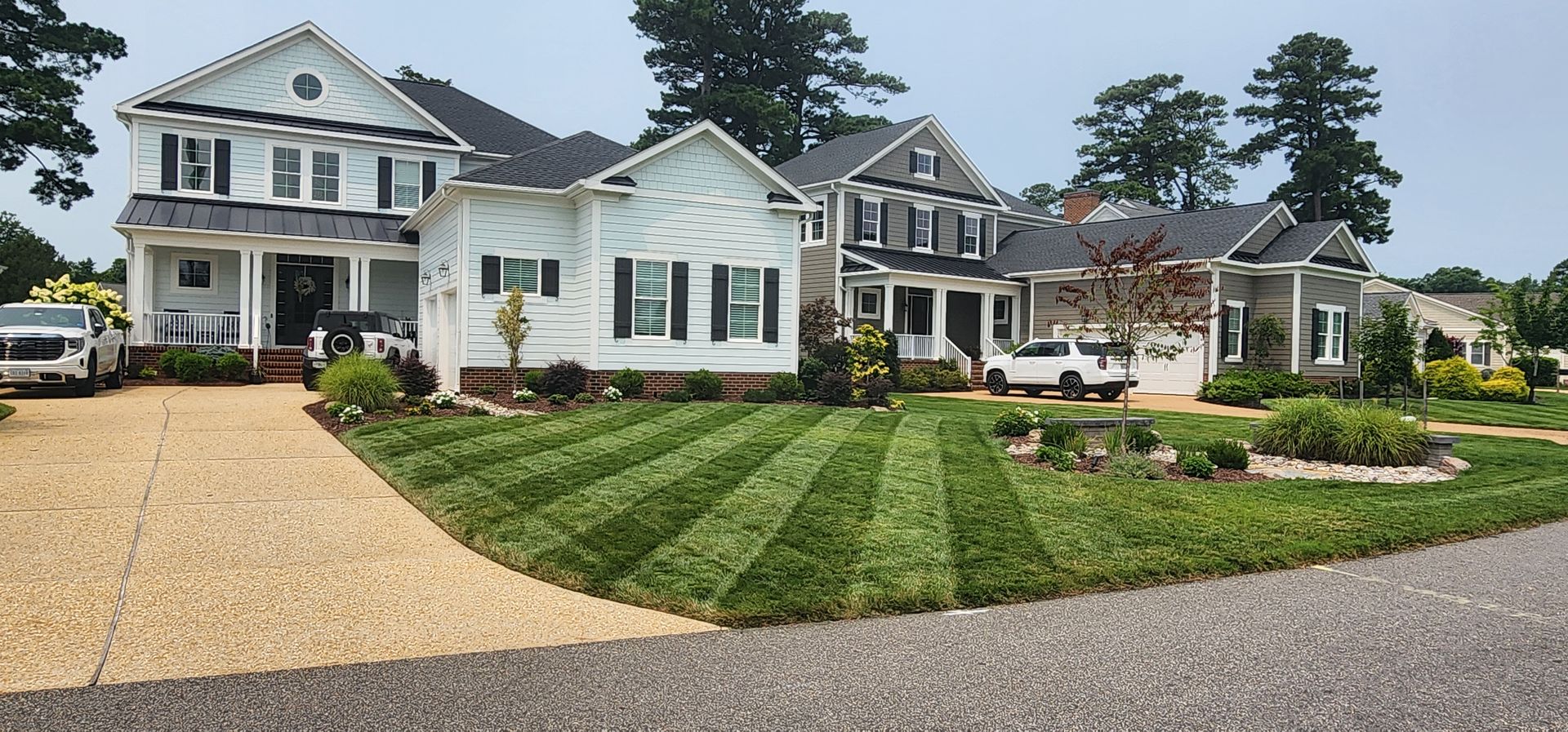 Row of white suburban homes with gravel driveways and manicured lawns under a cloudy sky