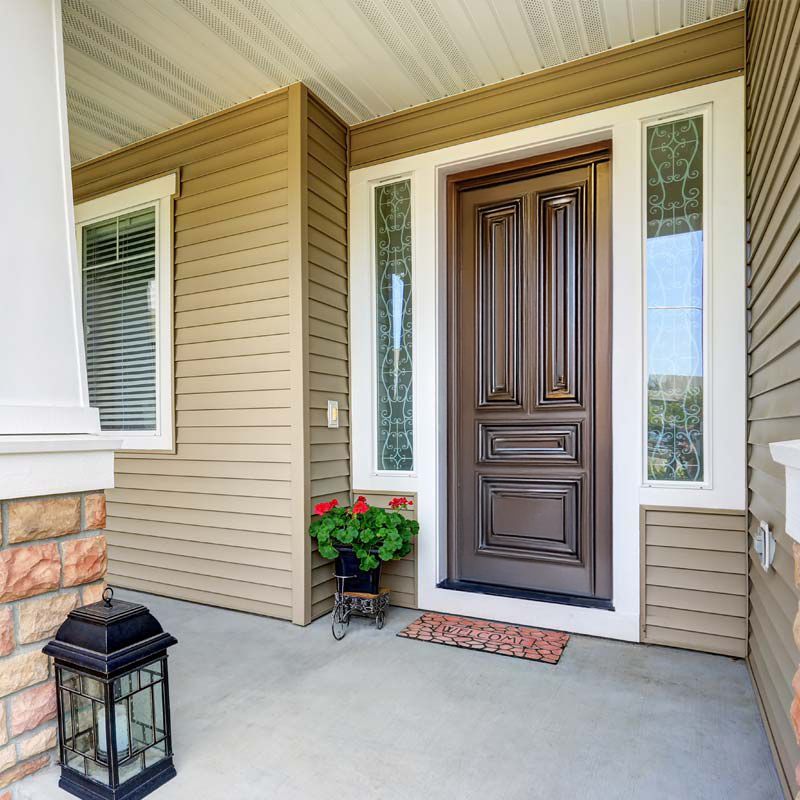 The front door of a house with a lantern and flowers on the porch.