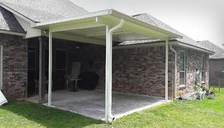 A brick house with a covered patio in the backyard.
