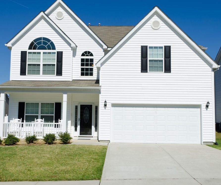 A white house with black shutters and a white garage door.