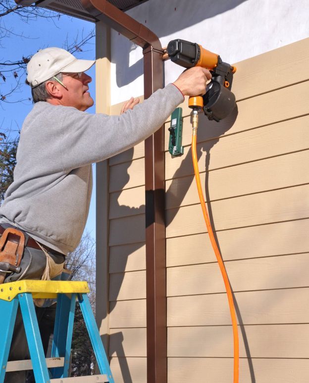 A man is installing a siding on a residential house.