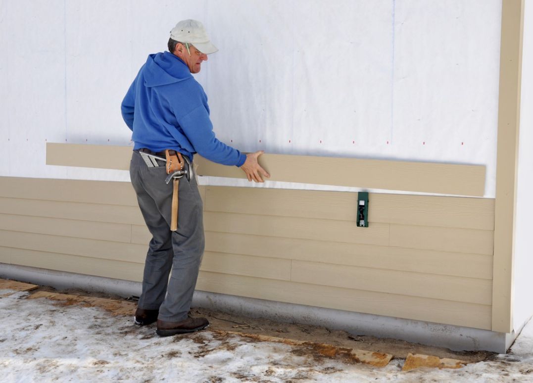 A man is measuring a wall with a tape measure.