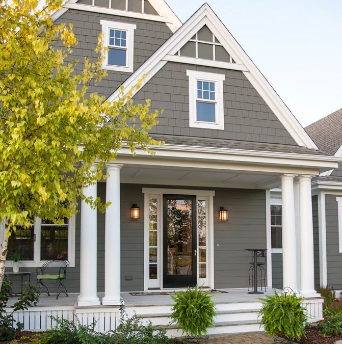 A gray house with a porch and white columns.