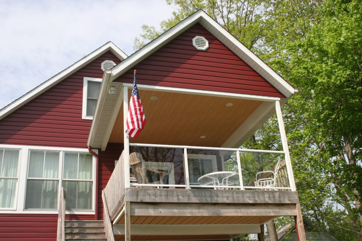 A red house with a balcony and an american flag.