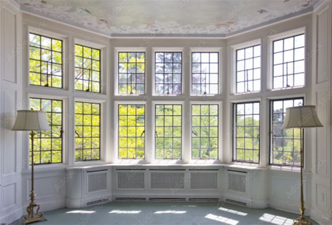 A room with a lot of windows and two lamps.