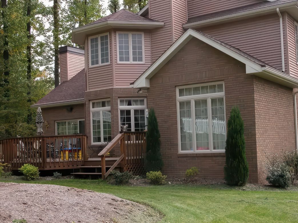 A large brick house with a deck and stairs.