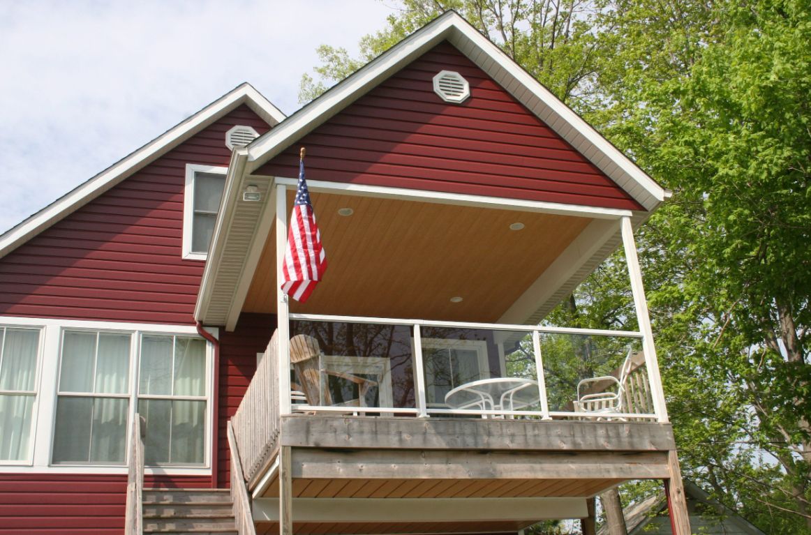 A red house with a balcony and an american flag.