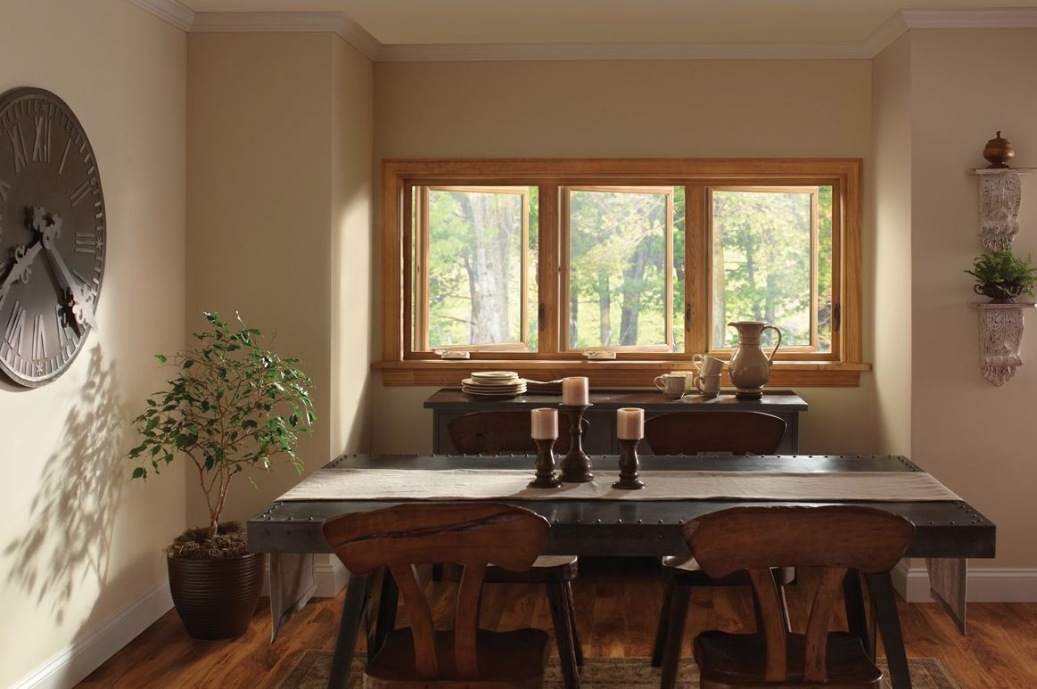A dining room with a table and chairs and a clock on the wall.