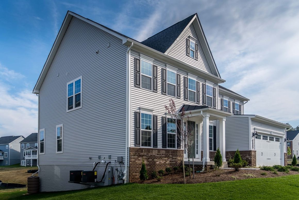 A large white house with a black roof is sitting on top of a lush green lawn.