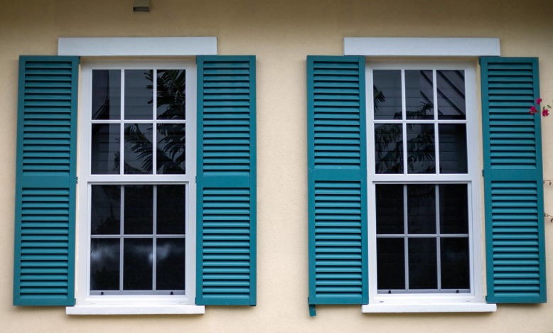 Two windows with blue shutters on a house