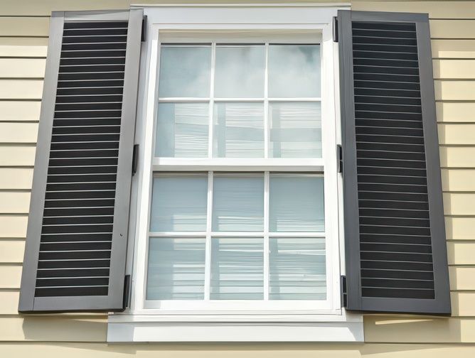A white window with black shutters on a house