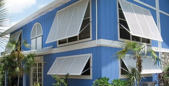 A blue house with white awnings on the windows