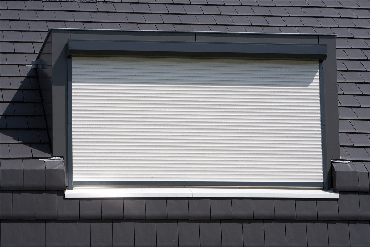 A window with a shutter on it is on a roof.