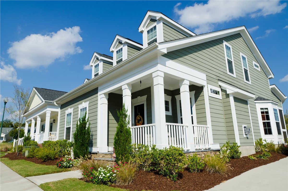 A green and white house with a large porch