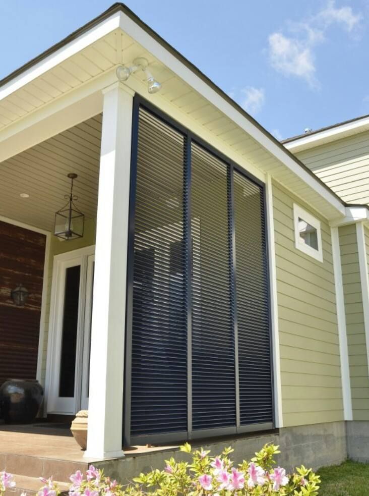 A house with a screened in porch and flowers in front of it