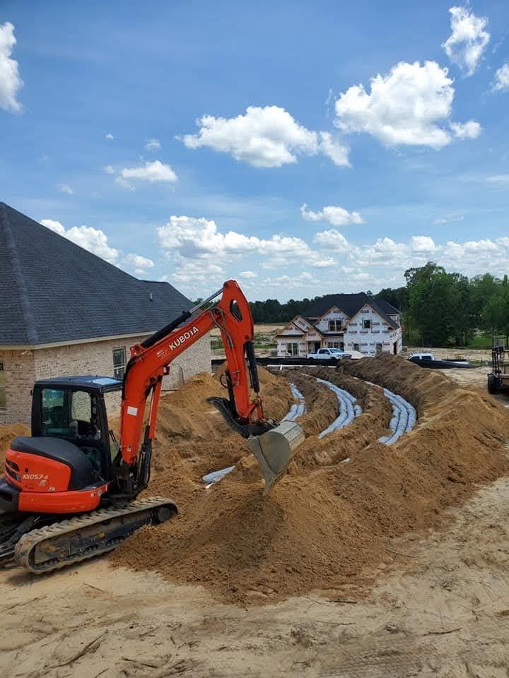 Orange excavator digging earth at a construction site under a cloudy blue sky