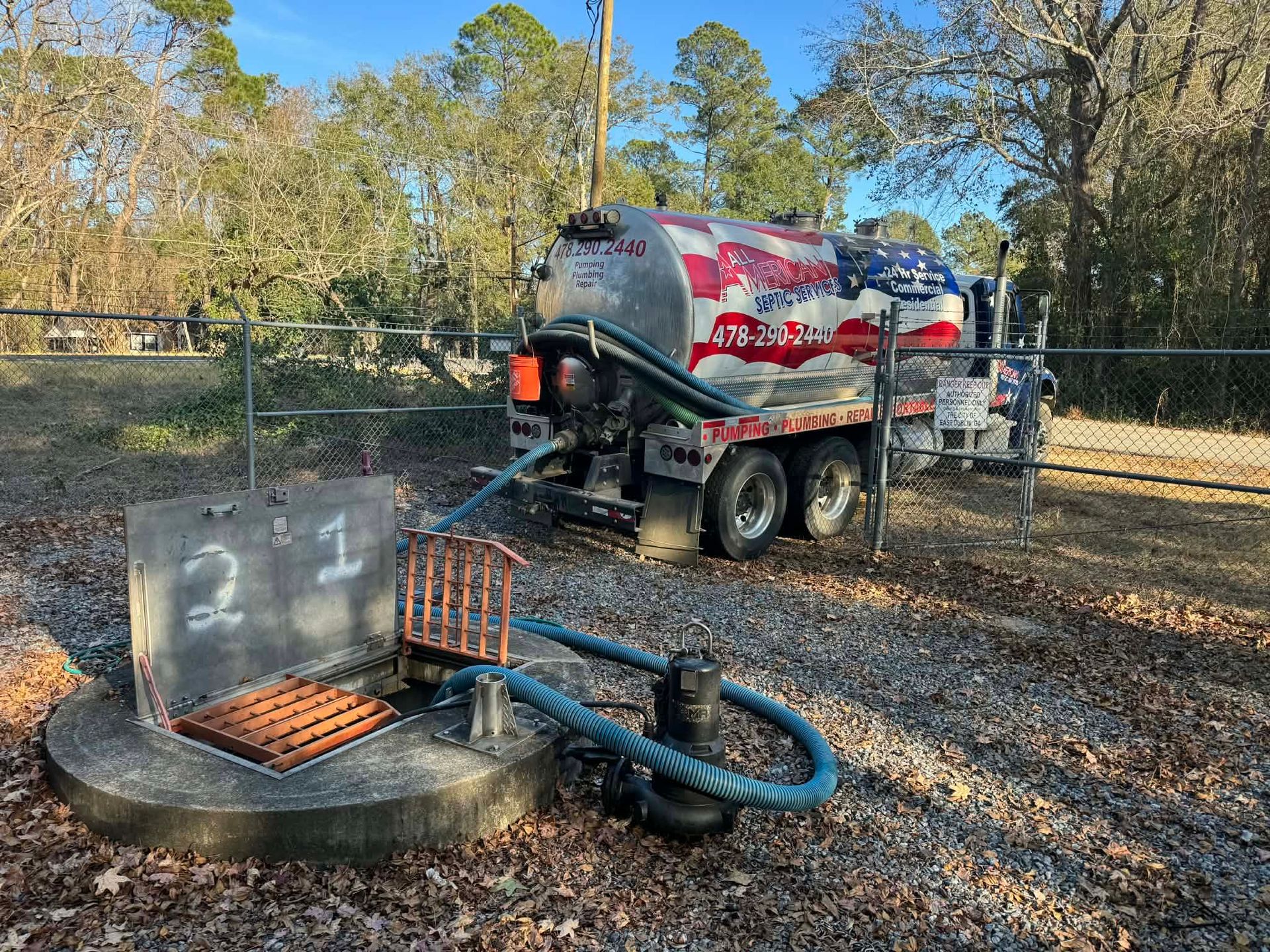 Portable wastewater tank and hose setup beside a vacuum truck in a wooded area