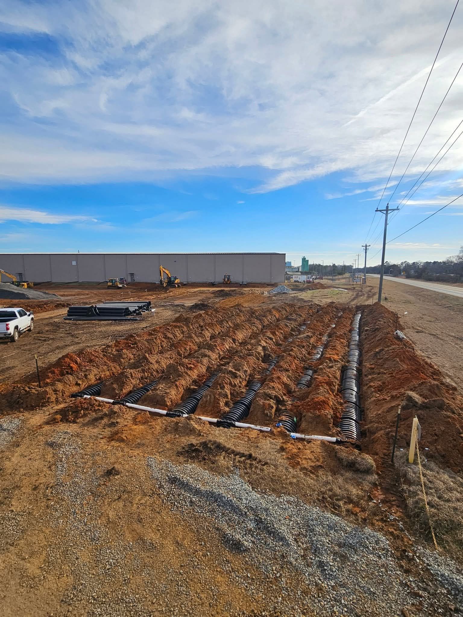 Solar farm under construction on a snowy, cloudy landscape with rows of panels and utility poles.