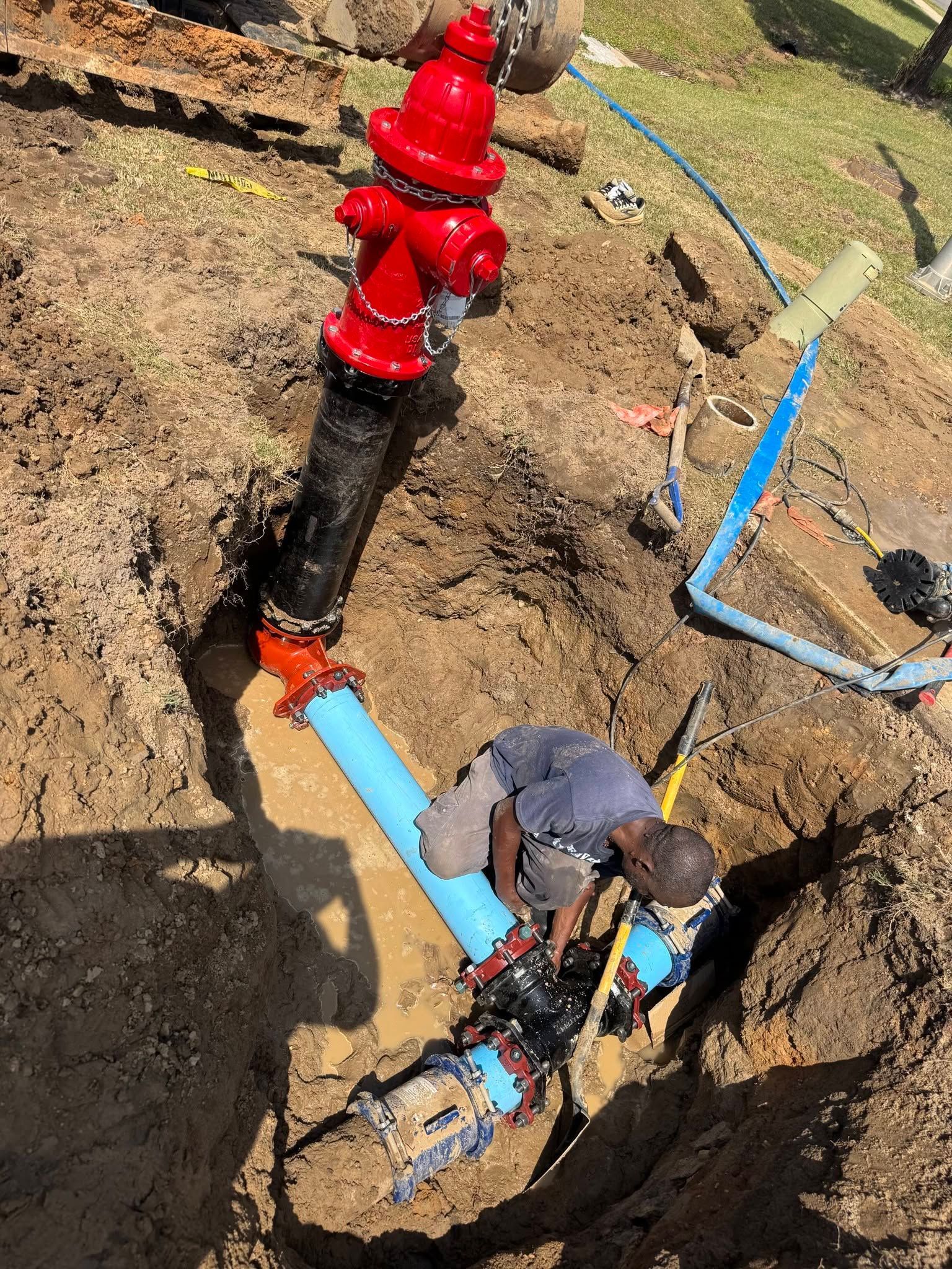 Utility workers repairing a blue water pipe in a dirt trench with a red valve assembly above ground