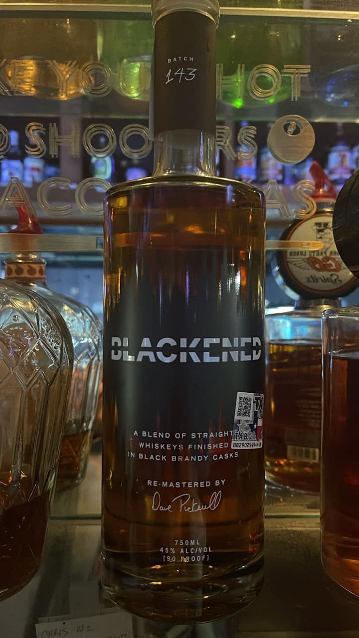 A bottle of blackened whiskey is sitting on a bar counter.