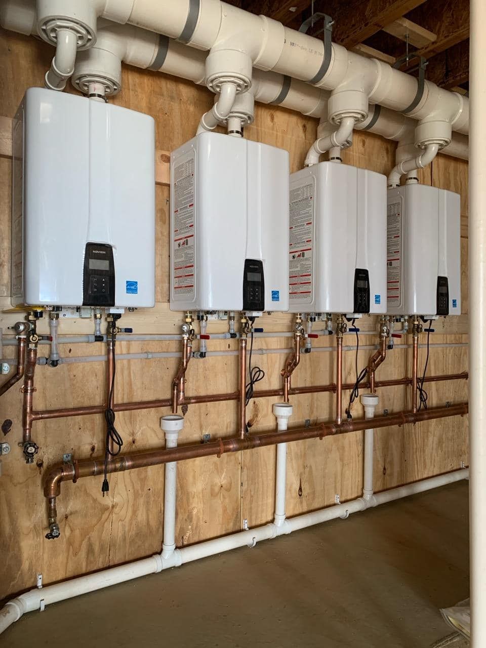 Water heaters are lined up along a wall.
