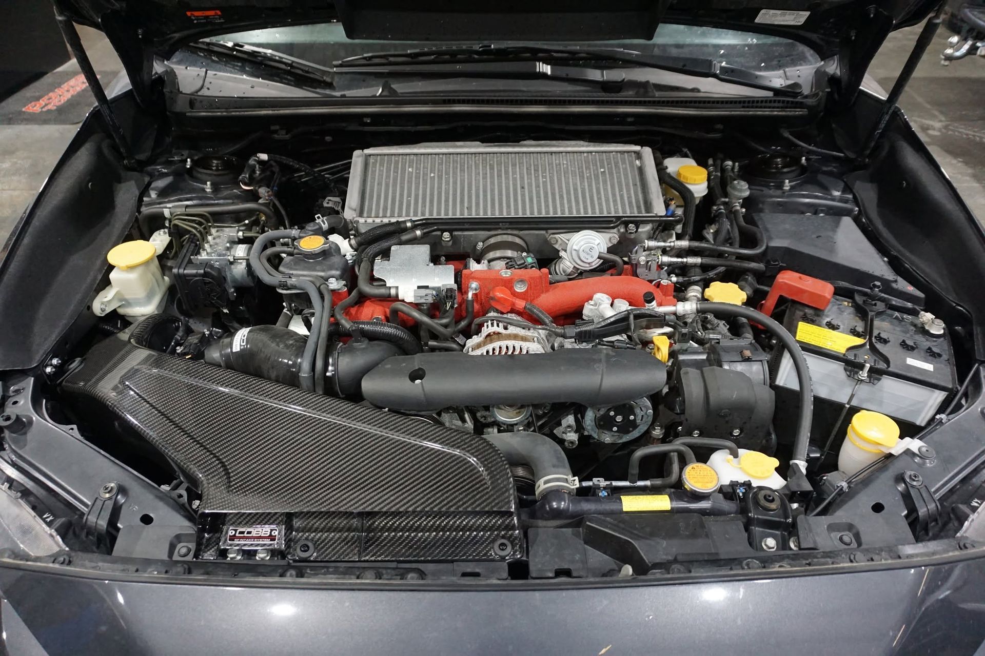 Car engine bay with black and red components, top-mounted intercooler, and open hood