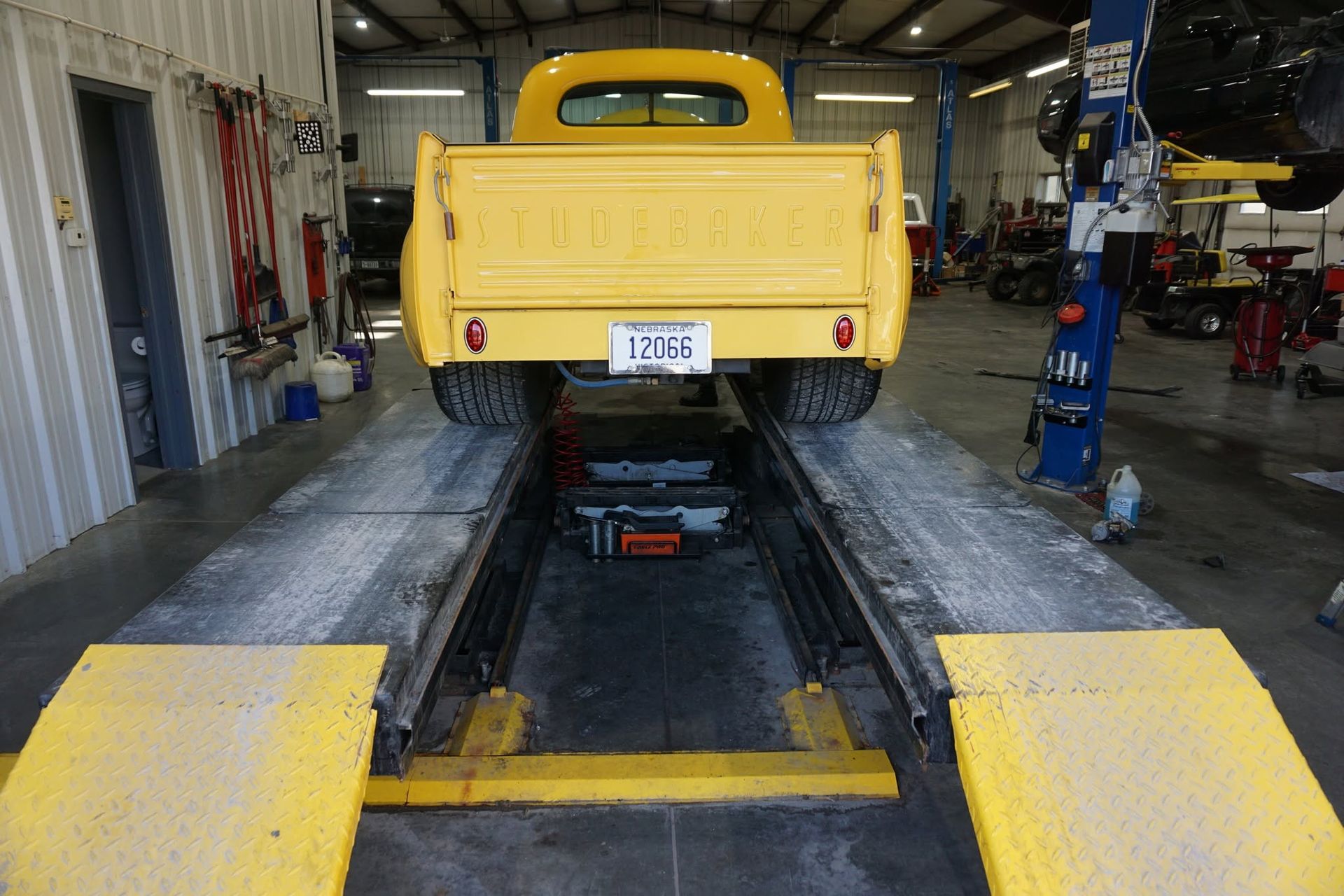 Yellow pickup truck on a shop lift inside an auto repair garage