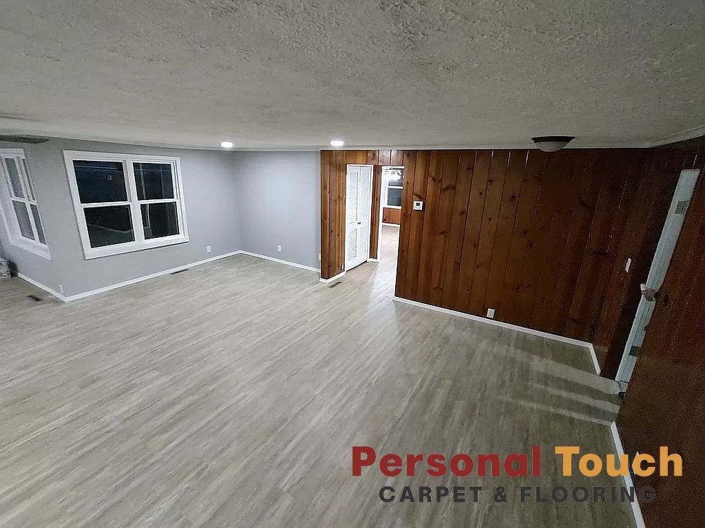Newly renovated interior with gray walls, wood paneling, and light wood-look flooring.