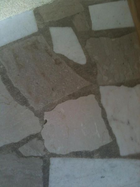 Irregularly shaped light stone floor tiles with gray grout.
