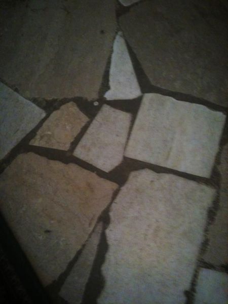 Stone floor with irregularly shaped, light-colored tiles and dark grout.