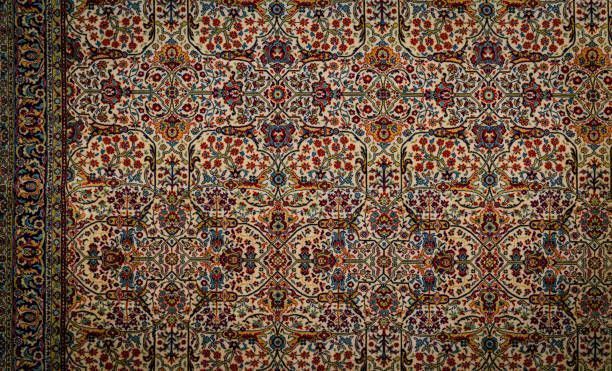 Close-up of a patterned carpet with floral and animal motifs in cream, red, blue, and gold.