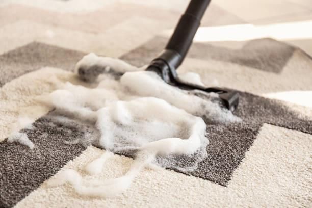 Vacuum cleaner nozzle removing soapy foam from a patterned carpet.